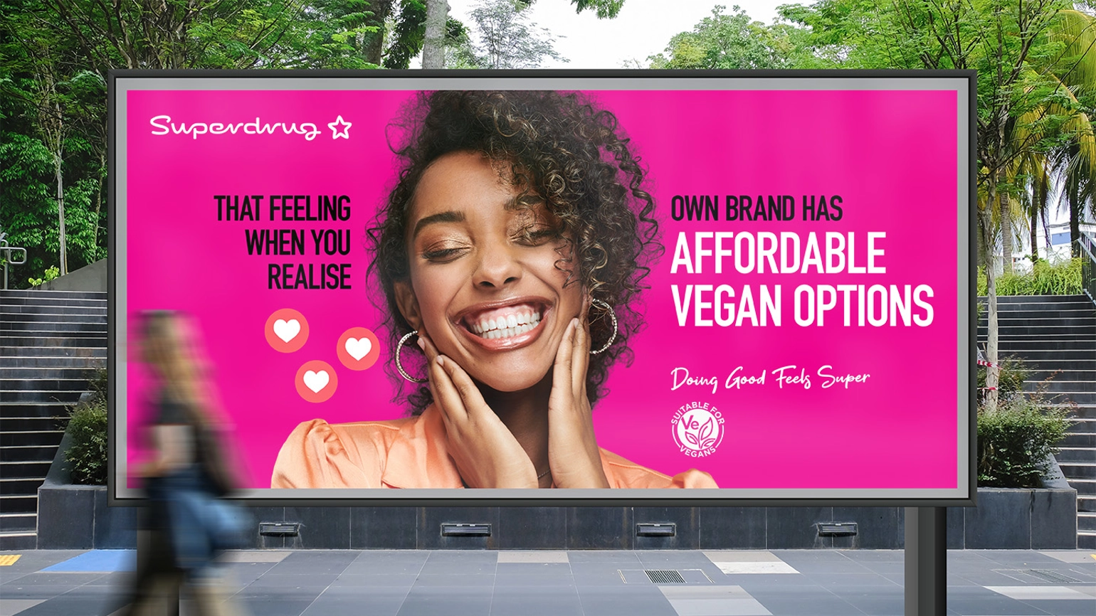 Image of the billboard which has an image of a happy woman with the Superdrug logo and the words that feeling when you realise own brand has affordable vegan options and the strapline doing good feels super
