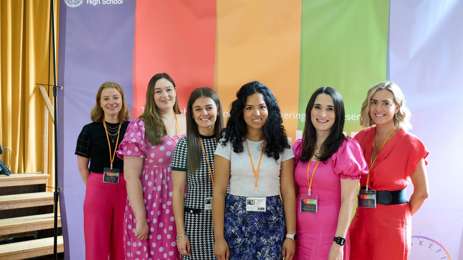 A group of six women, including RY's Rebecca Ward standing in front of a rainbow flag with Wakefield High School and EmpowerHer branding