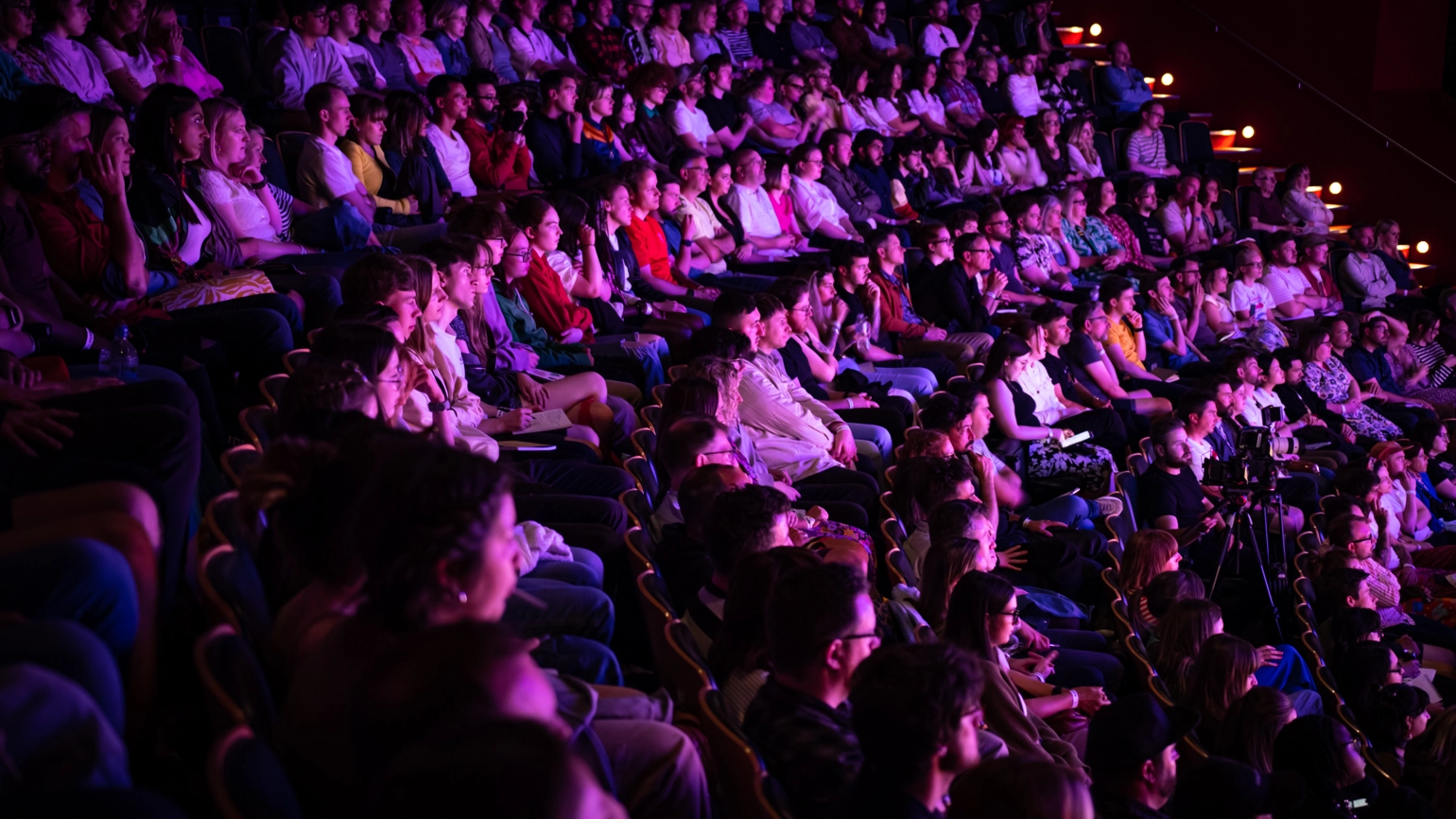 Photograph of an audience in purple light, attending Birmingham Design Festival