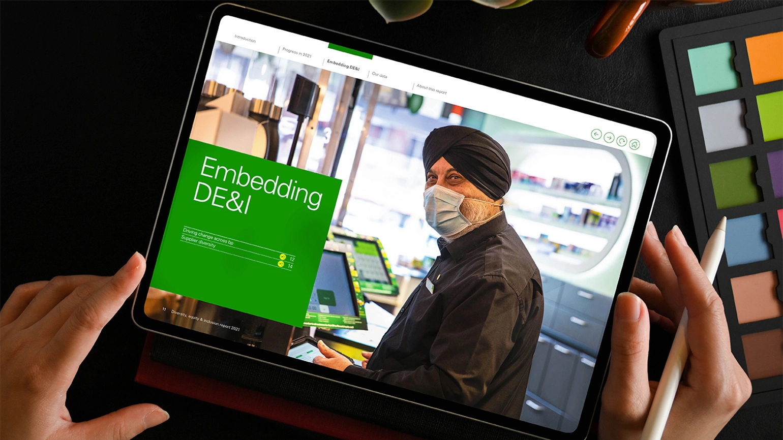 Example of report design within a tablet with a photo of a bp customer service worker wearing a mask on the right and then the title of embedding DE&I on the left