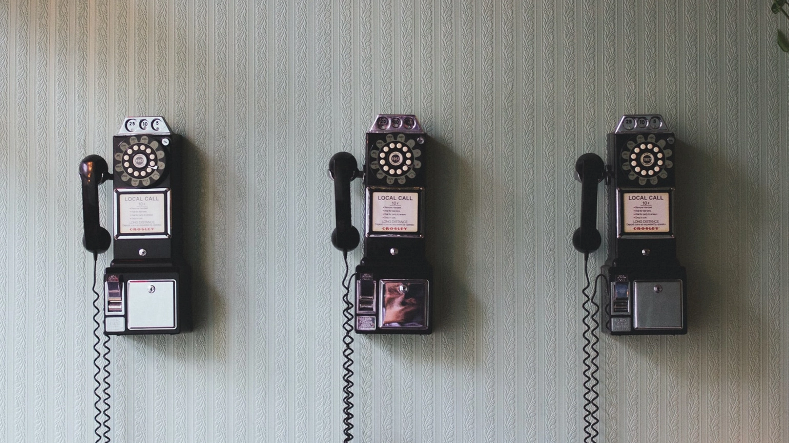 Three black telephones on the wall