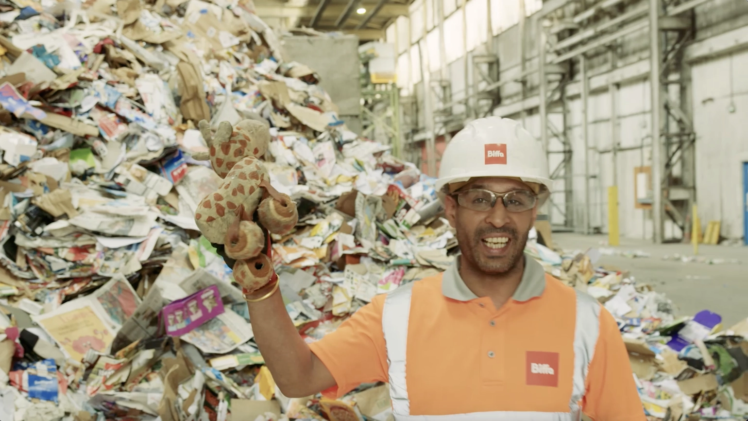 Photo of MRF worker in front of a pile of recycling