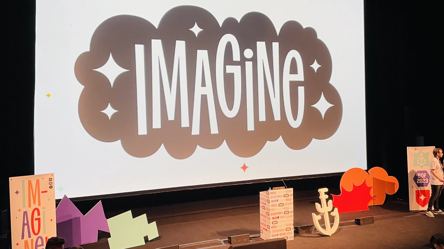 The stage at Birmingham Design Festival, showing a large screen that reads 'Imagine' in a cloud shape