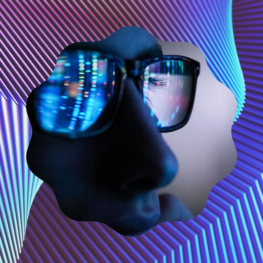 Image in a striped blue and purple frame, of a person wearing spectacles which reflect florescent coloured data on a computer screen